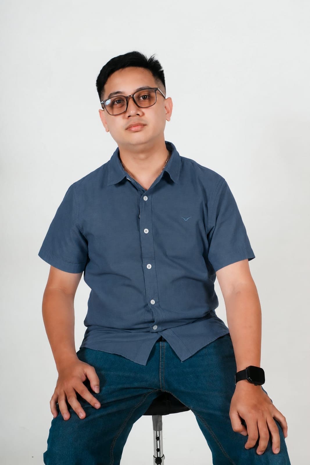 Carlo in a light blue shirt, in front of a white studio wall.